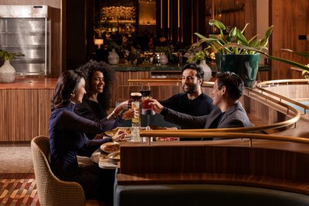 Grupo de amigos reunidos em uma mesa de restaurante de luxo realizando um brinde