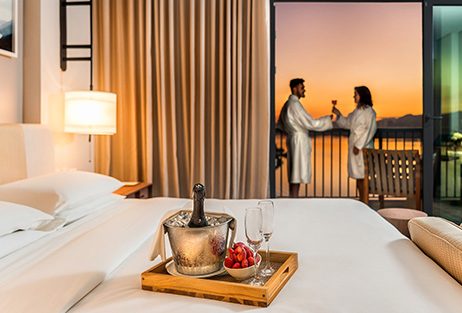 Casal hospedados em uma suíte do Grand Hyatt comemorando dia dos namorados com uma champanheira em cima da cama